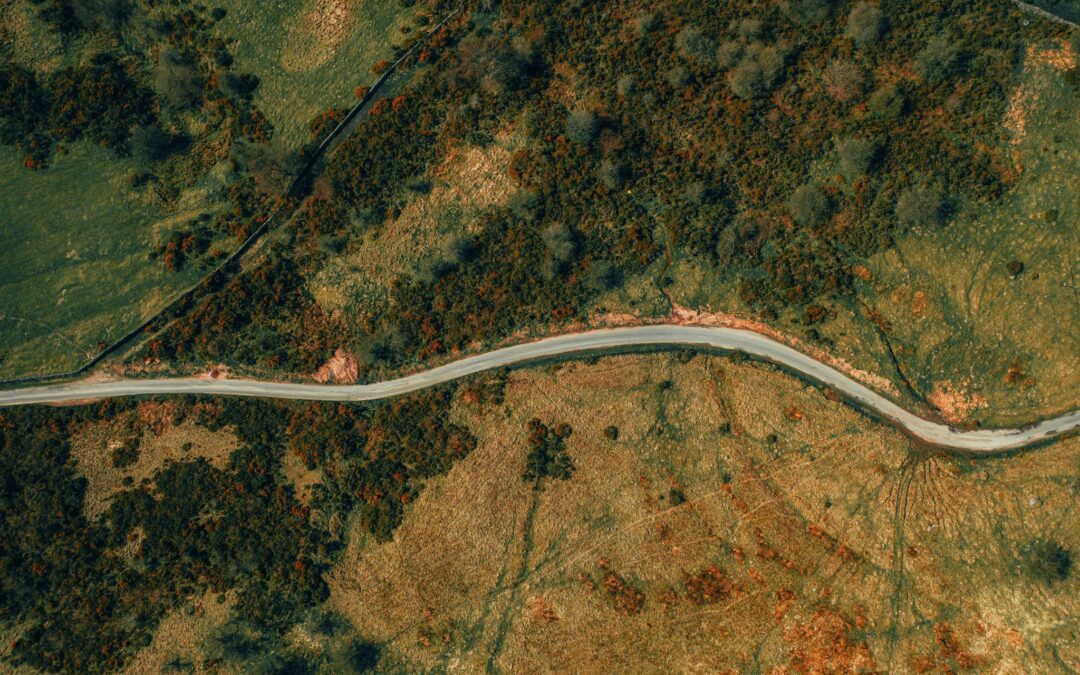 An aerial view of a vacant piece of land with a road passing through it.
