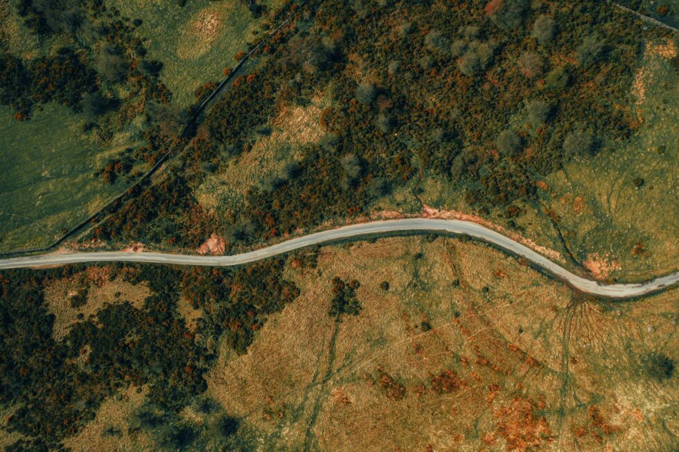 An aerial view of a vacant piece of land with a road passing through it.