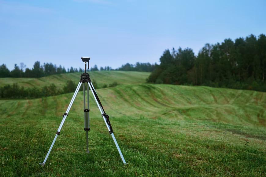 A land surveying equipment positioned precisely on a piece of land being surveyed.